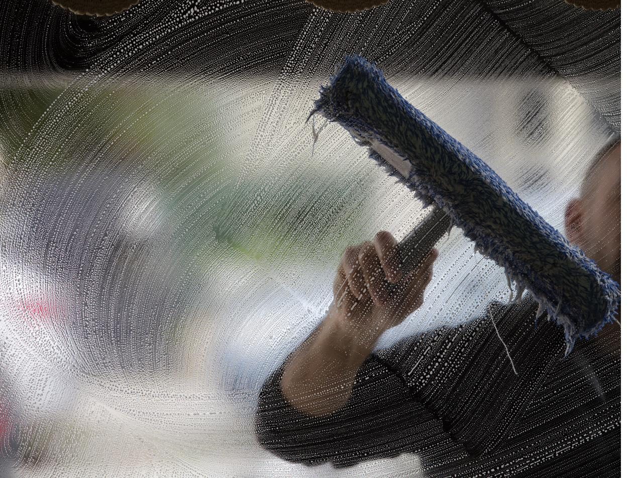 Fensterputzer in Münster reinigt ein Fenster mit Abzieher – Fensterreinigung Blitzsauber